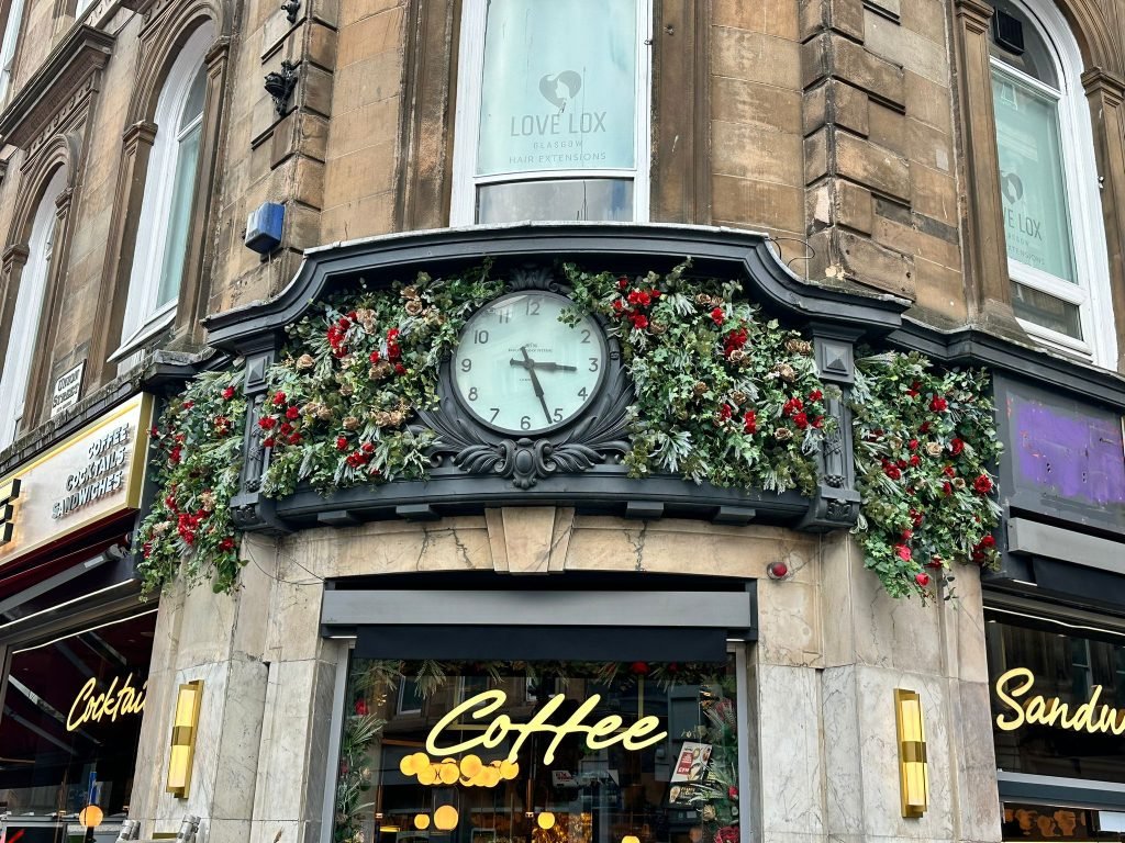 an exterior floral display with red and gold roses at the entrance of a coffee shop in glasgow